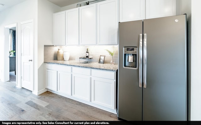 kitchen featuring backsplash, stainless steel fridge, white cabinetry, and light wood-type flooring