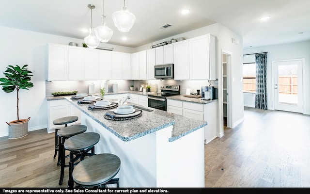 kitchen featuring pendant lighting, white cabinets, stainless steel appliances, and light wood-type flooring