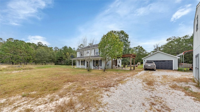 view of front of property featuring an outbuilding, covered porch, a front yard, and a garage