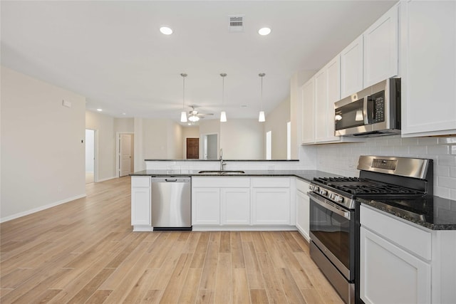 kitchen featuring appliances with stainless steel finishes, pendant lighting, sink, white cabinets, and light hardwood / wood-style floors