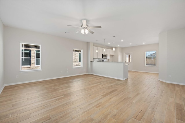 unfurnished living room with ceiling fan and light hardwood / wood-style flooring