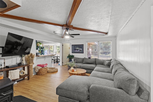 living room featuring ceiling fan, a healthy amount of sunlight, a textured ceiling, and light wood-type flooring