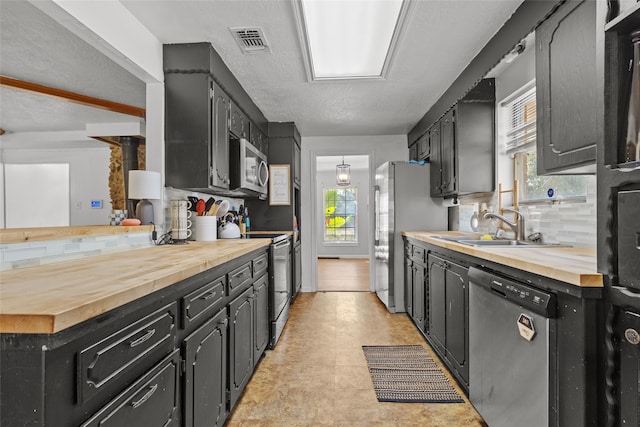 kitchen with wooden counters, sink, appliances with stainless steel finishes, and tasteful backsplash