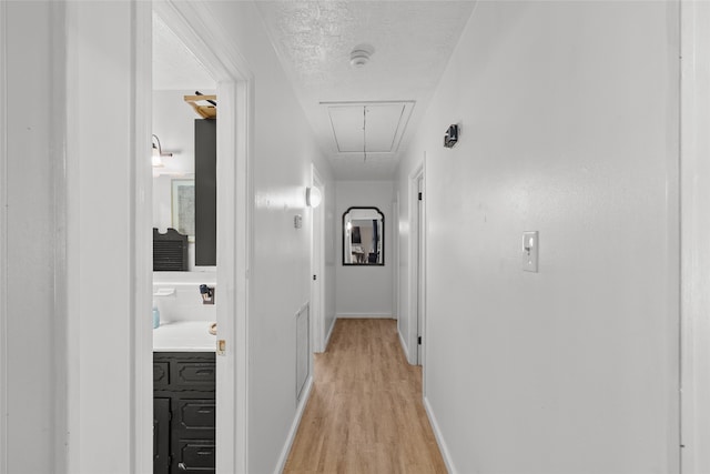 corridor featuring a textured ceiling and light hardwood / wood-style flooring