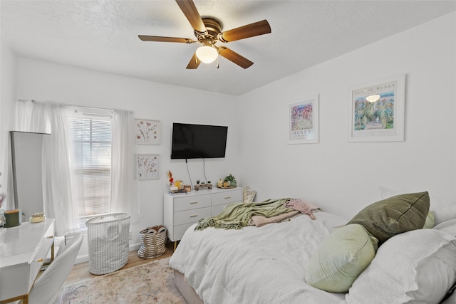 bedroom with ceiling fan, a textured ceiling, and light hardwood / wood-style floors