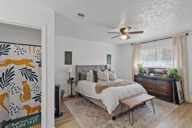 bedroom featuring ceiling fan, a textured ceiling, and light wood-type flooring