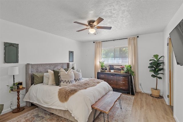 bedroom with ceiling fan, a textured ceiling, and light hardwood / wood-style flooring