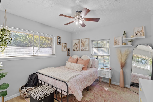 bedroom with light hardwood / wood-style flooring, multiple windows, a textured ceiling, and ceiling fan