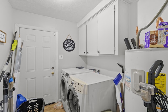 laundry room with water heater, cabinets, a textured ceiling, washing machine and dryer, and light hardwood / wood-style floors