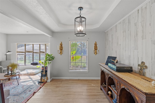 office space with a chandelier, a textured ceiling, light hardwood / wood-style floors, and a raised ceiling