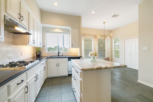 kitchen featuring white cabinets, sink, tasteful backsplash, dishwashing machine, and decorative light fixtures