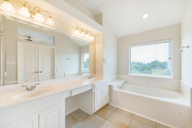 bathroom featuring vanity, a washtub, lofted ceiling, and plenty of natural light