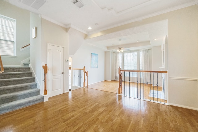 interior space featuring ceiling fan, a tray ceiling, light hardwood / wood-style floors, and crown molding