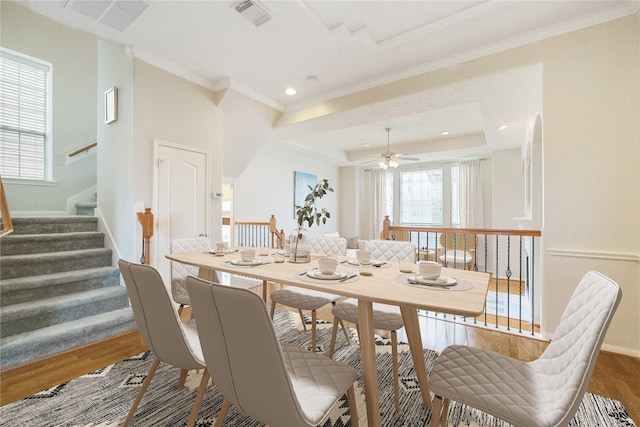 dining area with ornamental molding, hardwood / wood-style floors, ceiling fan, and a raised ceiling