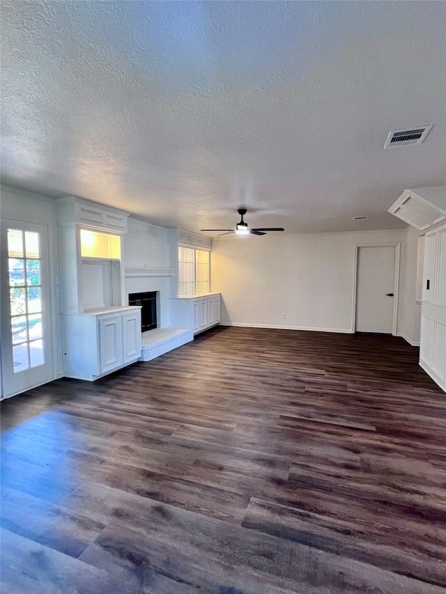 unfurnished living room with ceiling fan, a textured ceiling, dark hardwood / wood-style flooring, and a fireplace