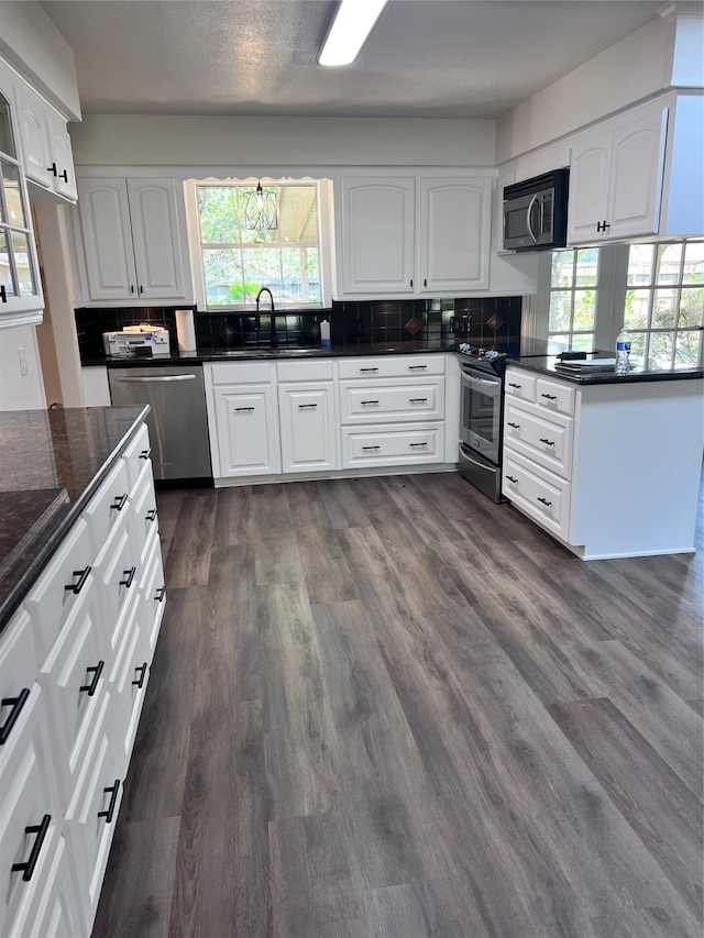 kitchen with appliances with stainless steel finishes, white cabinets, tasteful backsplash, and sink