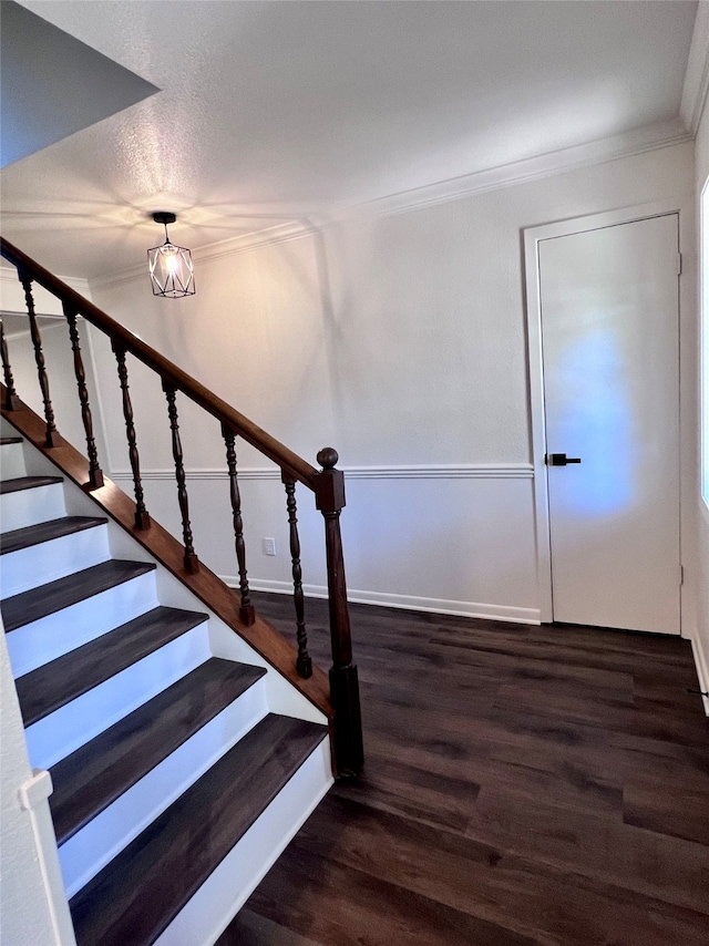 staircase featuring a textured ceiling, wood-type flooring, and ornamental molding