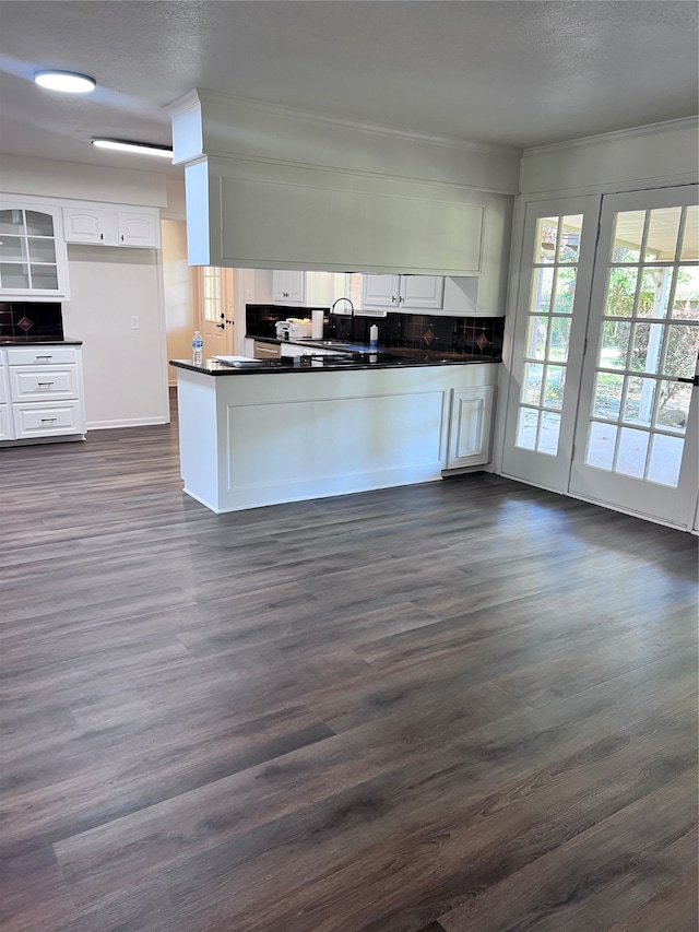 kitchen with sink, dark hardwood / wood-style flooring, kitchen peninsula, white cabinets, and ornamental molding