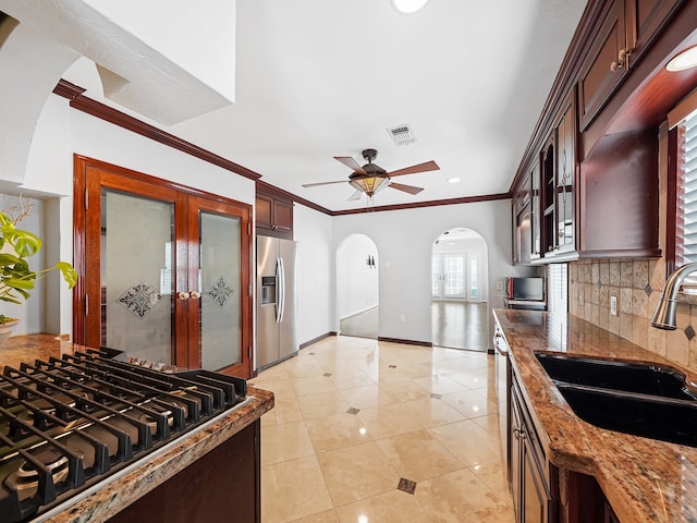 kitchen featuring tasteful backsplash, sink, stainless steel appliances, dark stone counters, and crown molding