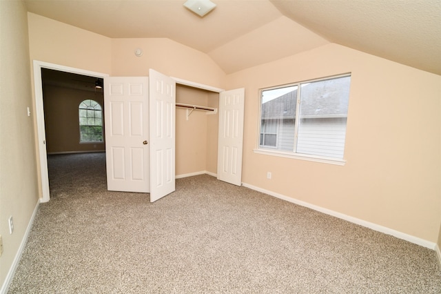 unfurnished bedroom with multiple windows, a closet, carpet flooring, and vaulted ceiling