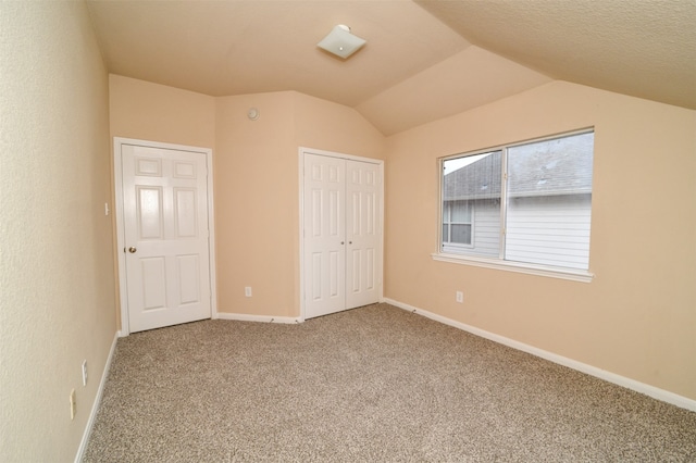 unfurnished bedroom with a closet, a textured ceiling, carpet flooring, and vaulted ceiling