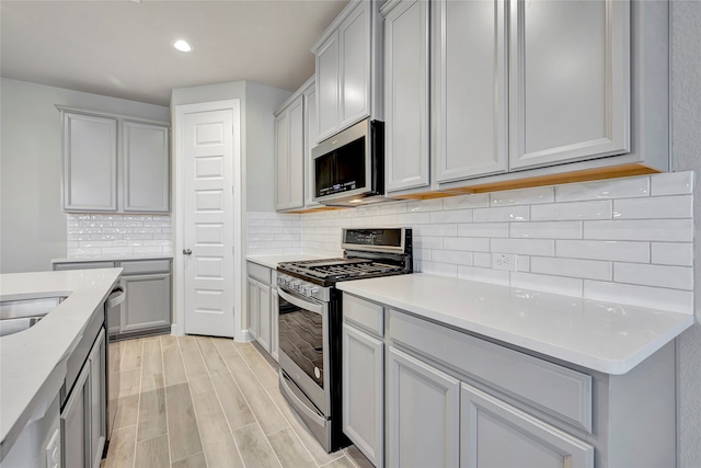 kitchen featuring gray cabinetry, stainless steel appliances, tasteful backsplash, and light hardwood / wood-style flooring