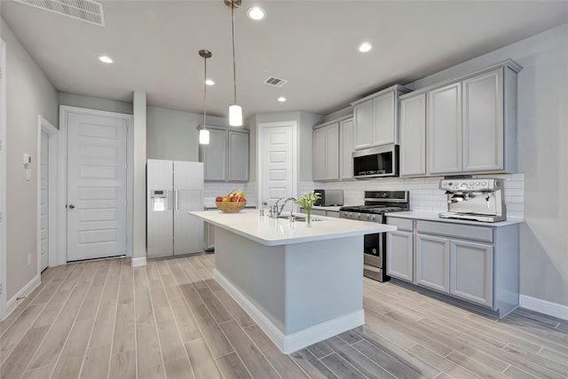 kitchen featuring light hardwood / wood-style flooring, stainless steel appliances, sink, pendant lighting, and gray cabinets