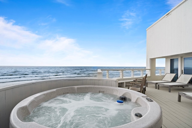 wooden deck featuring a view of the beach, a water view, and an outdoor hot tub