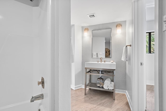 bathroom featuring hardwood / wood-style flooring, shower / bath combination, and sink