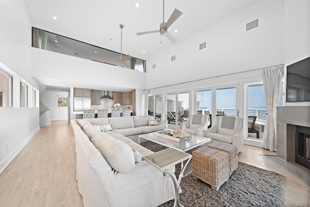 living room with light hardwood / wood-style flooring, high vaulted ceiling, and ceiling fan