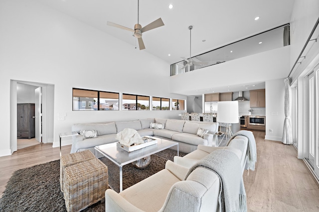 living room featuring ceiling fan, light hardwood / wood-style floors, and high vaulted ceiling