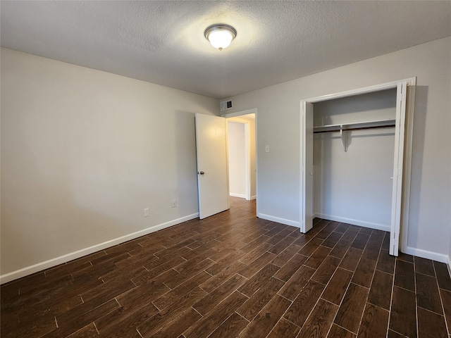 unfurnished bedroom featuring a textured ceiling, a closet, and dark hardwood / wood-style flooring