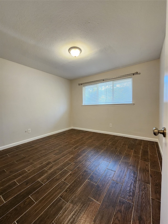 unfurnished room featuring a textured ceiling and dark hardwood / wood-style flooring