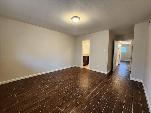 empty room with a textured ceiling and dark hardwood / wood-style flooring