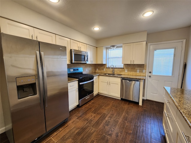 kitchen featuring sink, white cabinetry, stainless steel appliances, dark wood-type flooring, and light stone counters