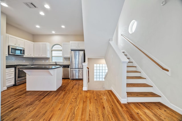 kitchen with a kitchen island, white cabinetry, appliances with stainless steel finishes, and decorative backsplash