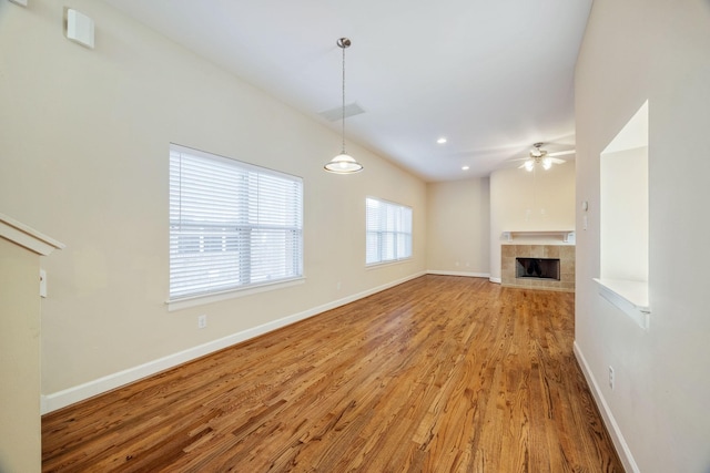 unfurnished living room with ceiling fan, a fireplace, and light wood-type flooring