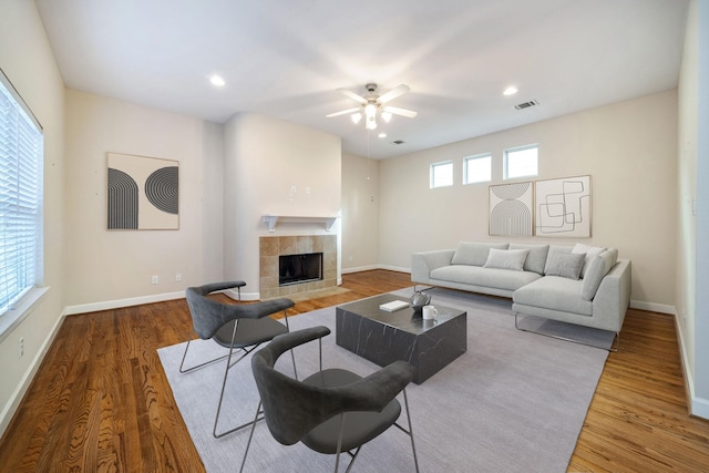 living room featuring a tile fireplace, hardwood / wood-style floors, and ceiling fan