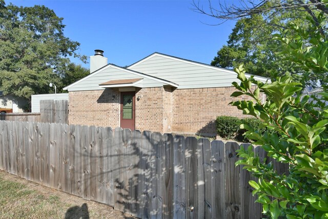 809 Pecan St, Brenham, TX 77833 - view of side of home featuring brick siding, fence, and a chimney