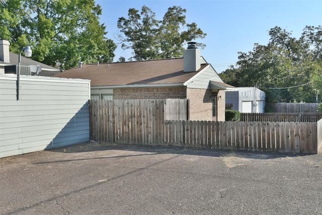 809 Pecan St, Brenham, TX 77833 - view of home's exterior featuring fence, a chimney, and brick siding