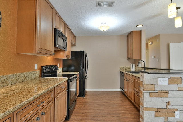 kitchen featuring sink, black appliances, pendant lighting, a textured ceiling, and light hardwood / wood-style floors