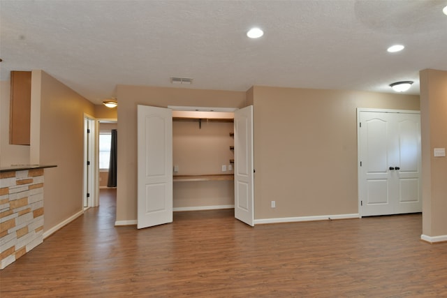 empty room featuring a textured ceiling, a stone fireplace, and wood-type flooring