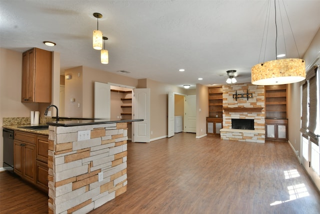 kitchen with a stone fireplace, sink, dark hardwood / wood-style floors, and hanging light fixtures