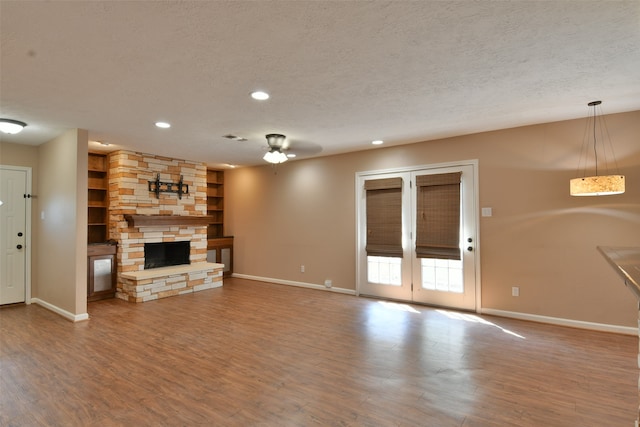 unfurnished living room featuring a textured ceiling, hardwood / wood-style flooring, a fireplace, and ceiling fan