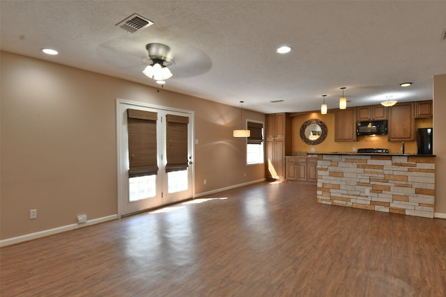 unfurnished living room featuring dark wood-type flooring, ceiling fan, a textured ceiling, and sink