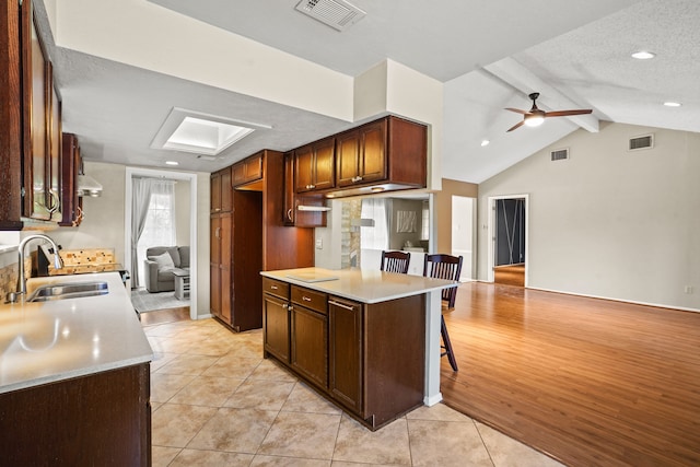 kitchen with a breakfast bar area, light hardwood / wood-style flooring, sink, a textured ceiling, and ceiling fan