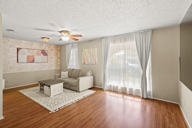 living room featuring ceiling fan, a textured ceiling, and hardwood / wood-style floors