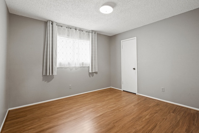 spare room with a textured ceiling and hardwood / wood-style floors