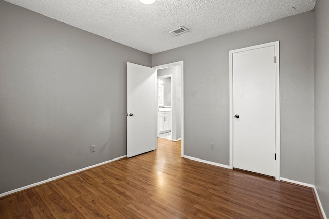 unfurnished bedroom with hardwood / wood-style floors and a textured ceiling