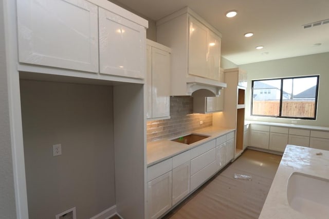 kitchen featuring sink, white cabinetry, black electric cooktop, and decorative backsplash